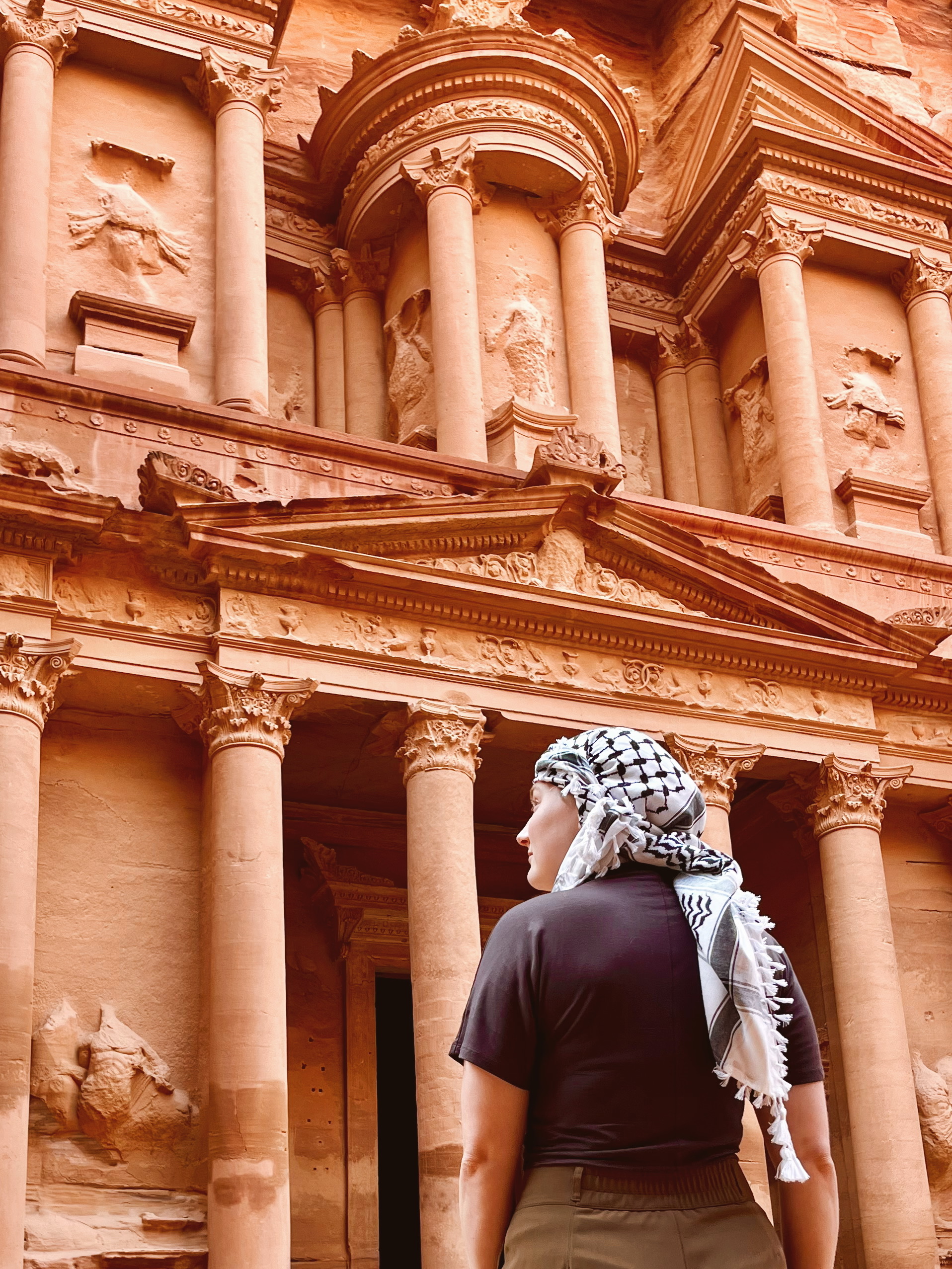 Terveys- ja turvallisuusvinkkejä havainnollistava kuva Jordaniasta - nainen seisomassa Petran Treasuryn edessä keväällä palestiinalainen kuffiyeh huivi päässään